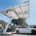 Electric car charging under a modern solar panel station, showcasing clean energy technology.